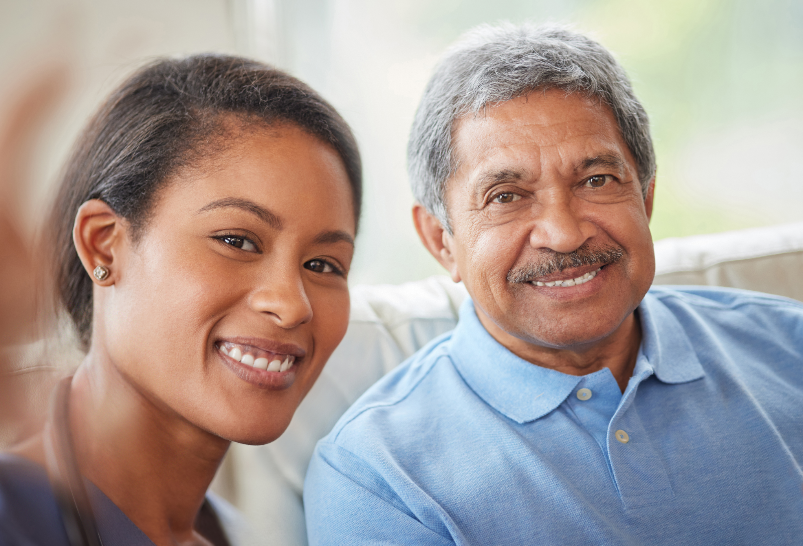 A smiling care advocate sitting with an older member at home
