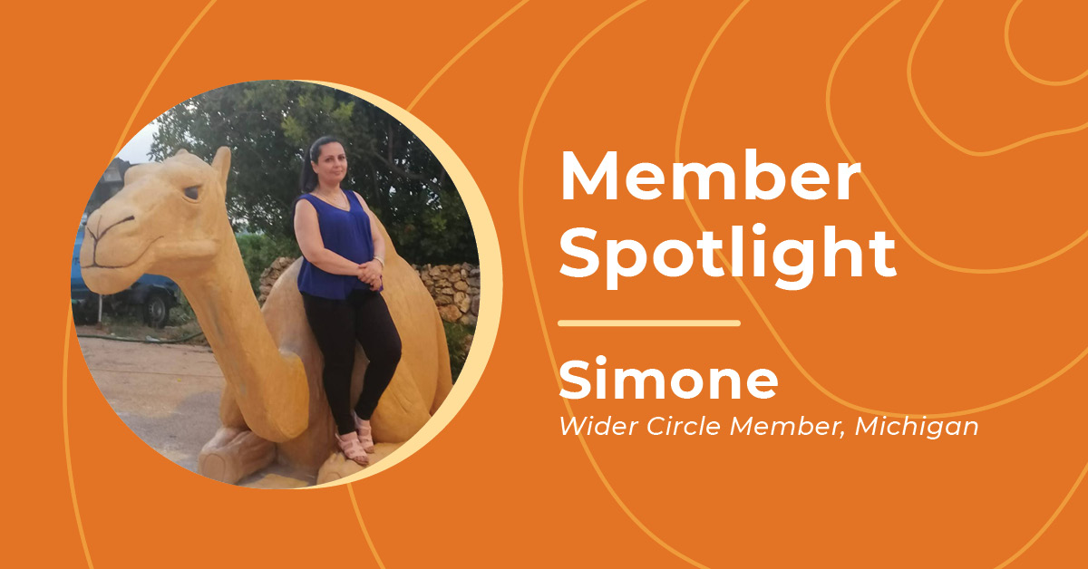 Female Wider Circle member Simone standing against a camel statue at a park smiling thoughtfully at the camera